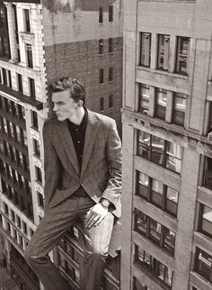 a man in a suit leaning on the ledge of a building