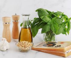 an assortment of food items displayed on a marble counter top with basil, garlic, and oil