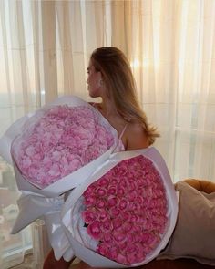 a woman holding two large bouquets of pink roses