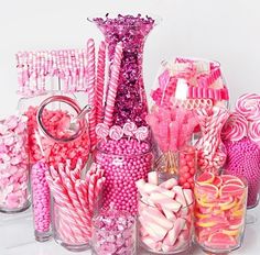 there are many pink and white candies in glass vases