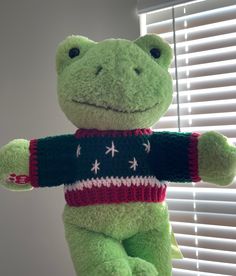 a green stuffed frog wearing a red, white and blue sweater