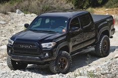 a black truck is driving on some rocks