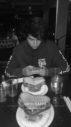 a person sitting at a table with plates of food and drinks in front of them