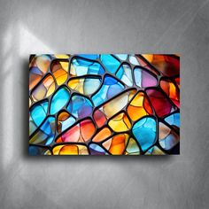 an abstract painting with multicolored glass on a gray wall in the shape of a mosaic