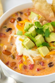 a white bowl filled with chicken tortilla soup and topped with avocado