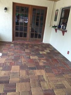 an empty patio with brick pavers and glass doors on the front door to a house