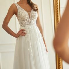 a woman in a wedding dress looking at herself in the mirror with her hand on her hip