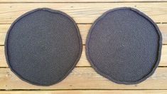 two black placemats sitting on top of a wooden table next to each other