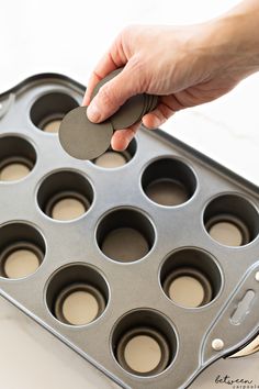 a person holding a coin in a muffin tin