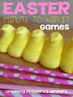 five yellow peeps lined up on top of a wooden table next to pink and white paper