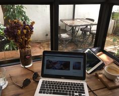 an open laptop computer sitting on top of a wooden table next to a cup of coffee