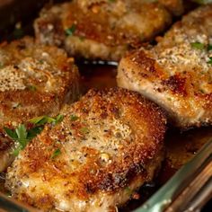 four pieces of meat in a pan with herbs on top, ready to be cooked