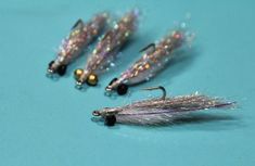 three different types of fishing flies on a blue surface with some gold and silver beads