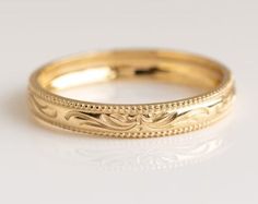 a gold wedding band with intricate designs on the sides and an engraved design on the inside