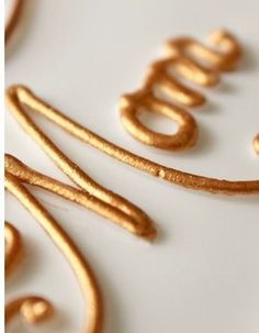 a close up of some type of writing on a white surface with gold colored paint