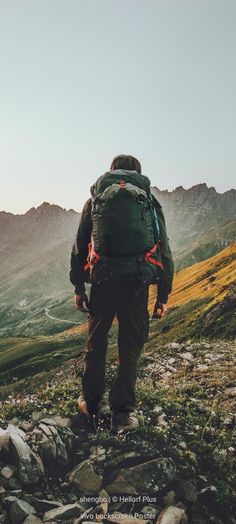 a man with a backpack walking up a mountain trail in the mountains at sunset or sunrise