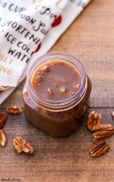 a jar filled with chocolate and pecans sitting on top of a wooden table next to a napkin