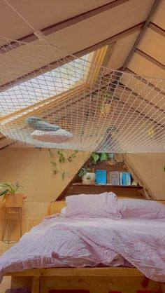 a bed with pink sheets and pillows in a lofted room under a slanted roof