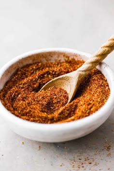 a small white bowl filled with spices and a wooden spoon on top of the bowl