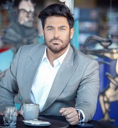 a man sitting at a table with a cup of coffee