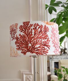 a red coral lamp shade on a table next to a potted plant in a living room