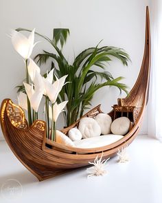 a wooden boat filled with lots of white flowers next to a potted palm tree