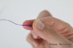 a person is holding something with one hand and the other has purple thread on it