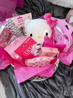 a hello kitty gift basket on a bed with pink tissue and other items in it