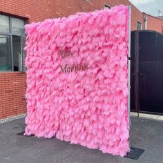 a pink sign that is on the side of a building in front of a brick wall