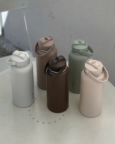 four different colored water bottles sitting on top of a white table next to each other