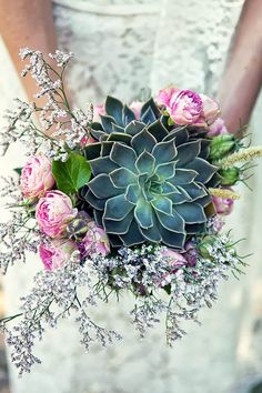 a bride holding a bouquet of flowers and succulents