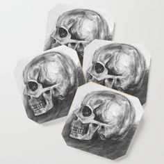 four skull coasters with black and white ink on paper, each featuring a human skull