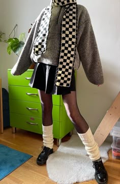 a woman standing in front of a green dresser wearing a scarf and black shoes with white socks