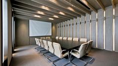 an empty conference room with white chairs and a projector screen in the middle of it