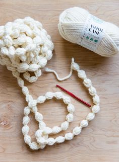 two balls of yarn sitting on top of a wooden table next to a ball of yarn