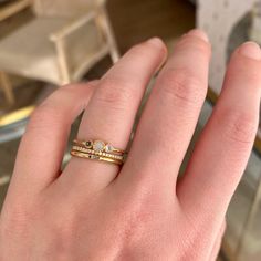 a person's hand with a gold ring on top of it and two diamonds in the middle