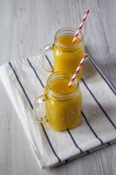 two mason jars filled with orange juice on top of a towel