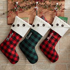 three christmas stockings hanging on a brick wall next to a wooden sign with the word grandma written on it