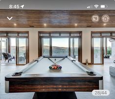 a pool table in the middle of a living room with sliding glass doors leading outside