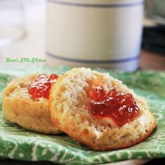 two biscuits with jam on them sitting on a green napkin next to a white cup