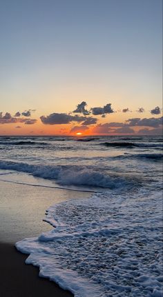 the sun is setting over the ocean with waves crashing on the shore and clouds in the sky