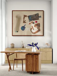 a painting hangs on the wall above a wooden table