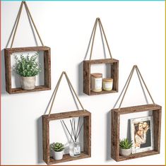 three wooden hanging shelves with plants and pictures on them, each holding a planter