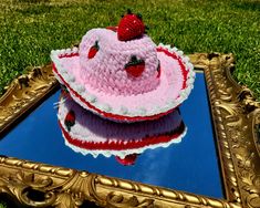 a pink and white cake sitting on top of a blue surface in front of a gold frame