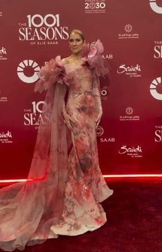 a woman in a pink dress standing on a red carpet with her arms around her body