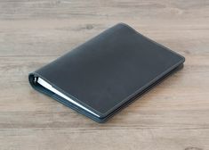 a black leather notebook sitting on top of a wooden table