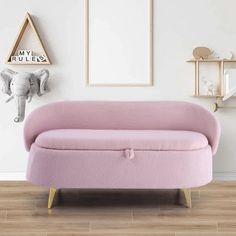 a pink couch sitting on top of a hard wood floor next to a white wall