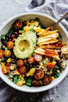 a white bowl filled with black beans, avocado and other vegetables on top of a gray cloth