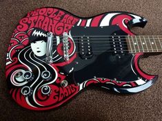 a red and black guitar sitting on top of carpet