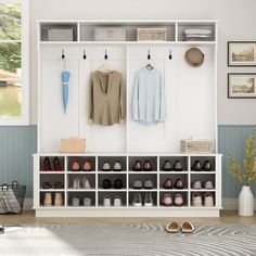 a white coat rack with shoes and sweaters hanging on the wall next to it